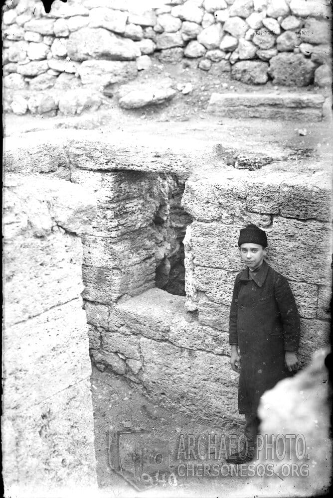 Мальчик в раскопанном помещении т.н. Монетного двора. 1904 год
